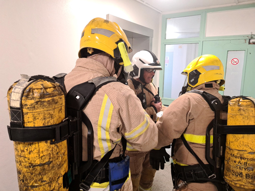 Firefighters wearing breathing apparatus are briefed by their Watch Manager