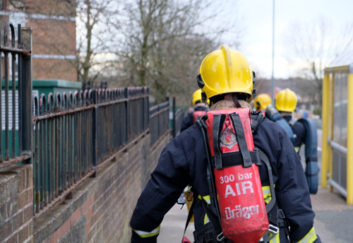 Firefighters from GMFRS carry BA cylinders into the building