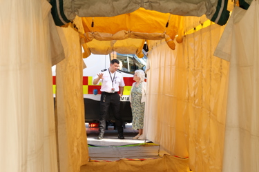 Photo looking through a Mass Decontamination tent as Baroness Blake of Leeds CBE liaises with National Resilience personnel.